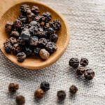 image of a black pepper in a wooden spoon