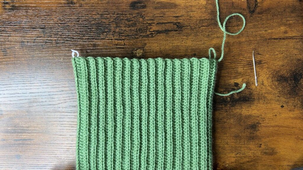 Image showing the top of the crochet cat ear beanie being sewn closed with whip stitches