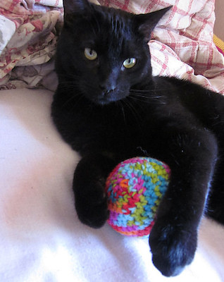 Close up of a crochet ball cat toy showing the texture of the yarn and crochet stitches