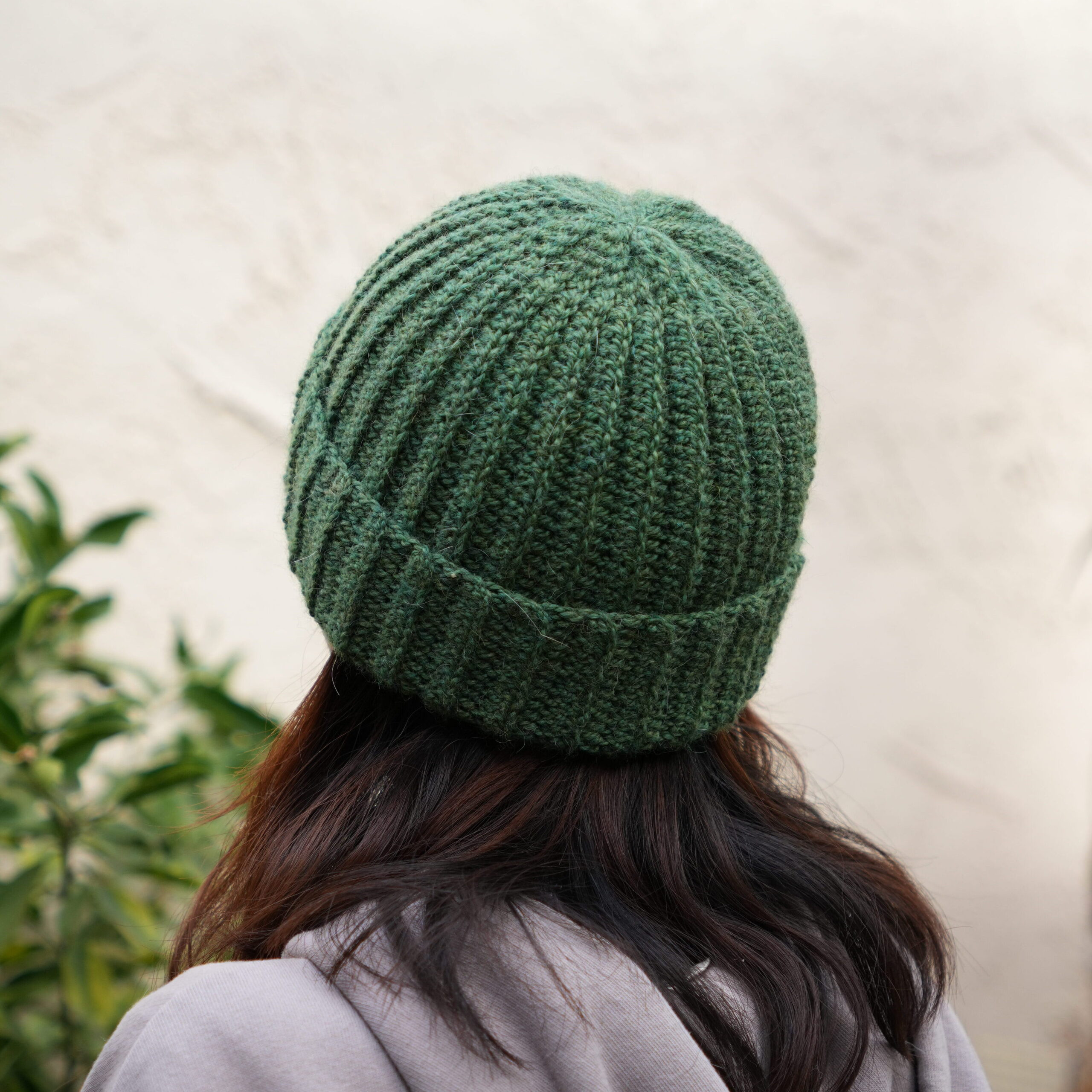 Image of a person wearing a grey crochet ribbed beanie from the back