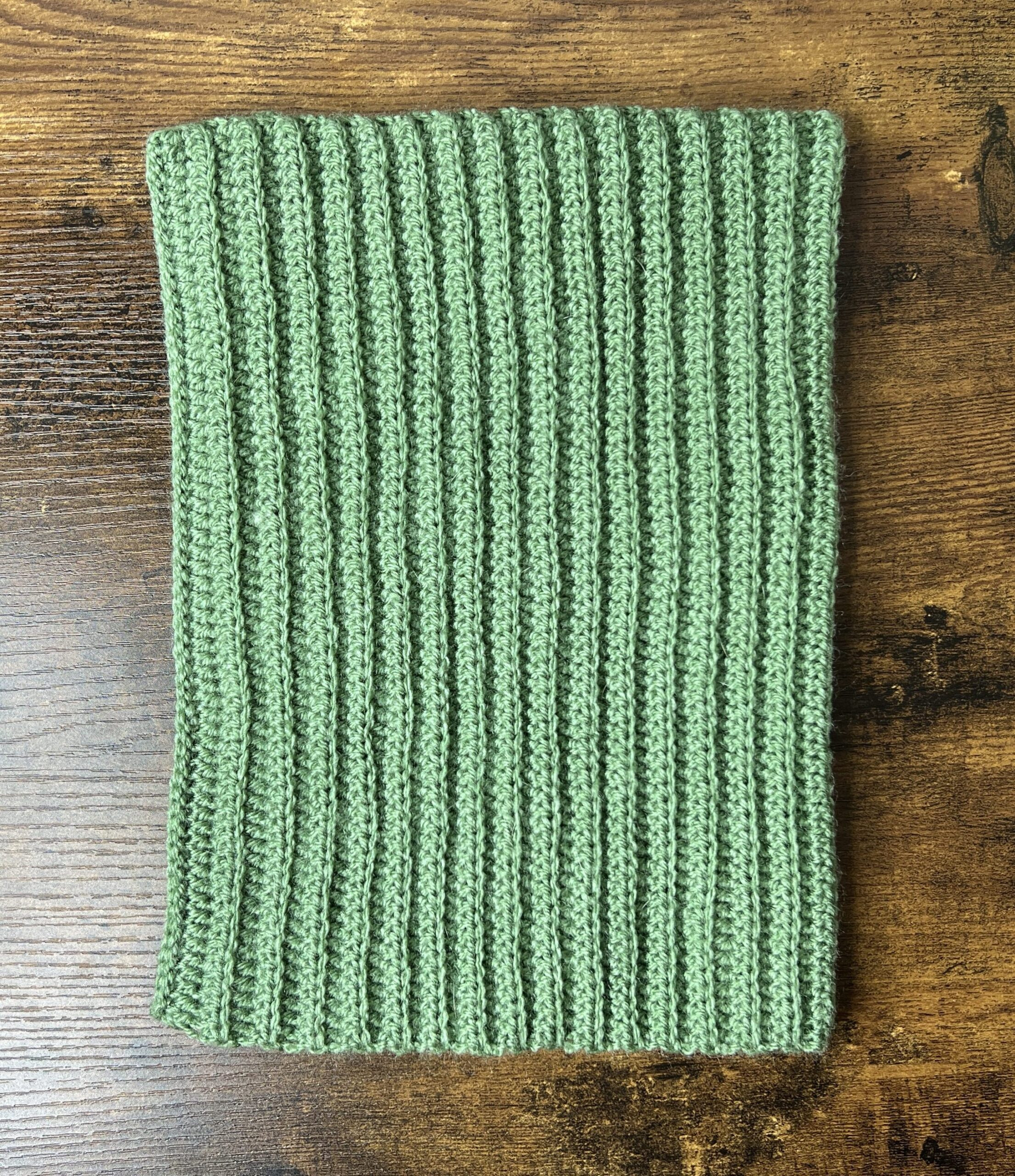 Close up of a folded cream colored crochet cat ear beanie showcasing the stitch texture
