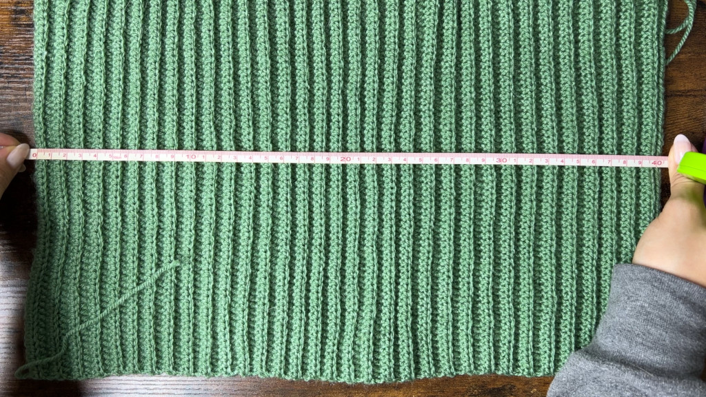 Still image from the video demonstrating how to check the size of the crochet beanie rectangle by wrapping it around the head
