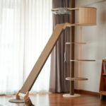 Two kittens playfully engage with a tall cat tree, showcasing its multiple levels and scratching surfaces.