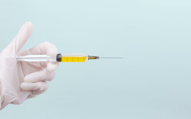 A gloved hand holds a needle and syringe