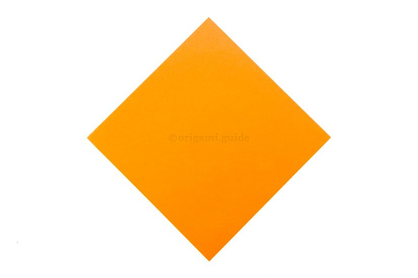The back side of the origami paper, typically white, facing upwards on a flat surface