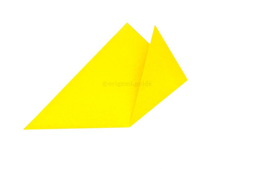 Folding the right corner upwards and to the right to create one of the cat's ears