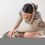 woman petting cat while eating